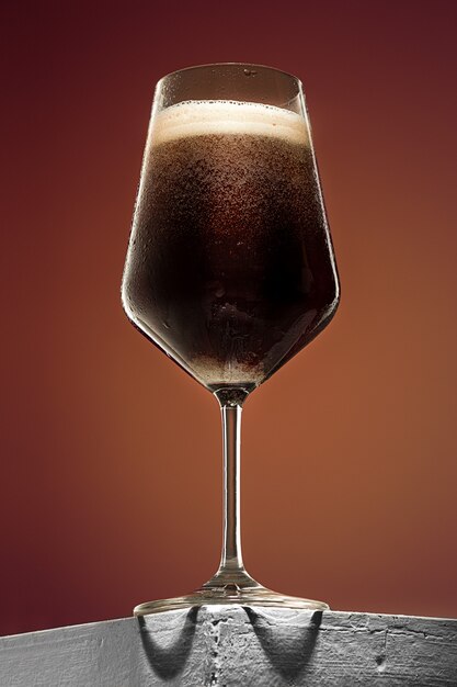 古い木製のテーブルに冷たい泡状の黒ビールのグラス