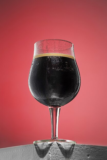 Glass of cold frothy dark beer on an old wooden table