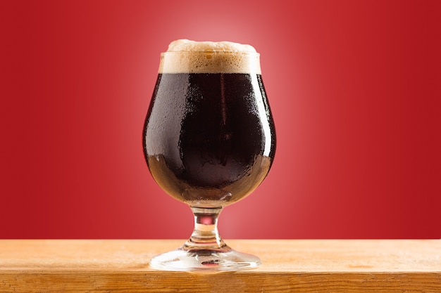 Free photo glass of cold frothy dark beer on an old wooden table