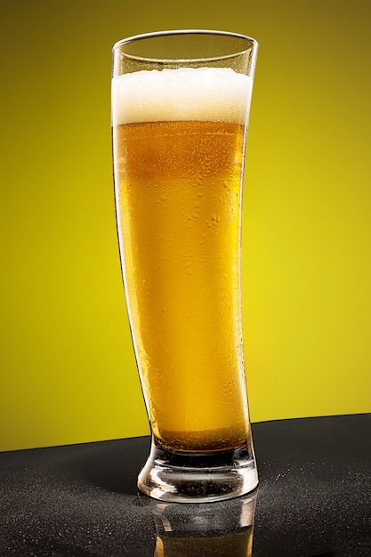 Glass of cold frothy lager beer on an old wooden table