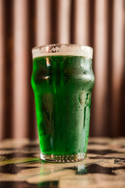 Glass of cold green drink on table