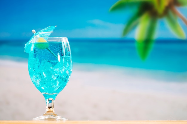 Glass of cooling blue drink decorated with olive and umbrella 