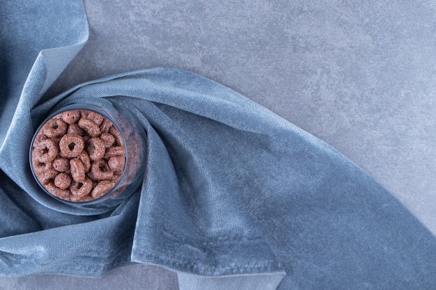 A glass of corn rings on a piece of fabric , on the blue background.