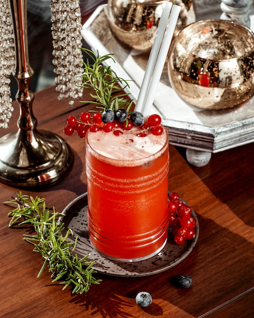 Free photo glass of cranberry cocktail garnished with cranberry and blueberry