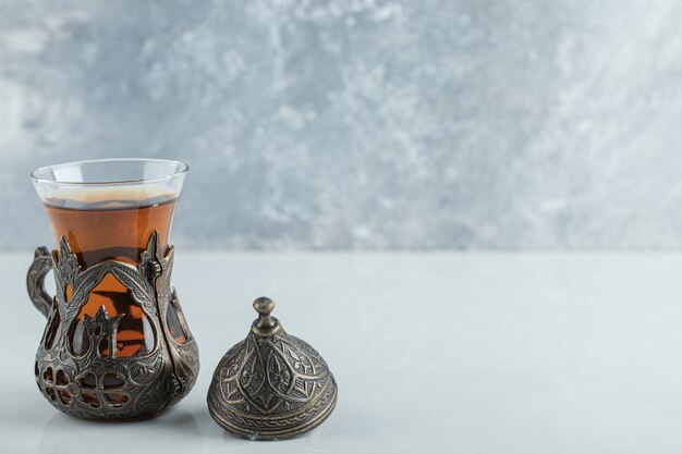 A glass cup of aroma tea on white.