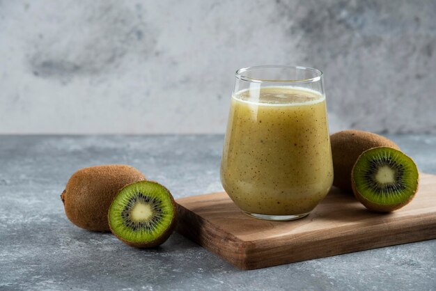 A glass cup of delicious kiwi juice on wooden board. 