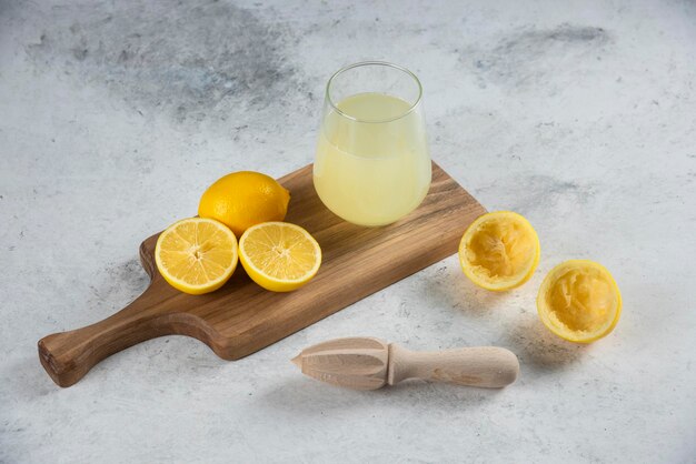 A glass cup of fresh lemon juice on a wooden board.