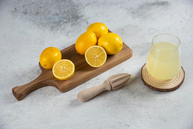 A glass cup of fresh lemon juice on a wooden board.