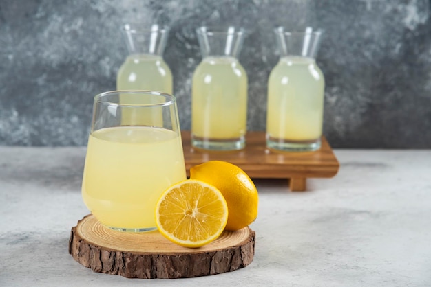 A glass cup of fresh lemon juice on a wooden board.