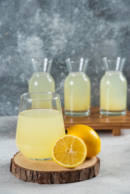 Free photo a glass cup of fresh lemon juice on a wooden board.