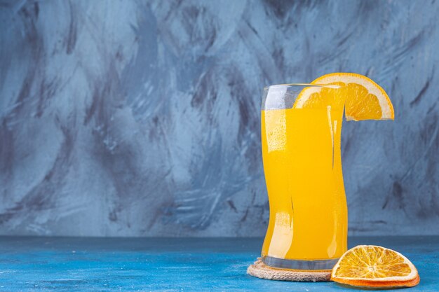 A glass cup of fresh orange juice placed on a colorful background. 