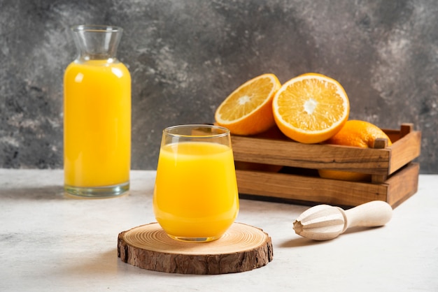 A glass cup of fresh orange juice on wooden board.