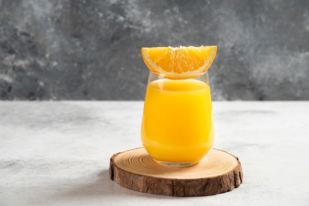 A glass cup of fresh orange juice on wooden board.