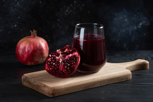 A glass cup of fresh pomegranate juice on wooden board. 