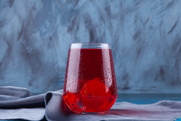 A glass cup of fruit juice placed on a tablecloth . 