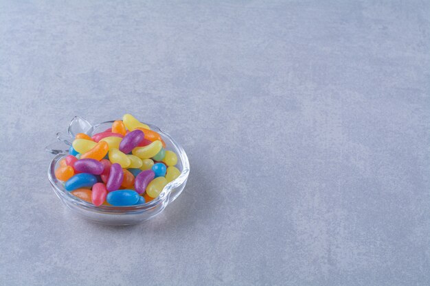 A glass cup full of colorful bean candies on gray background.High quality photo