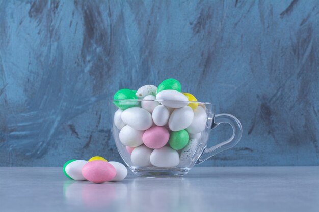 A glass cup full of colorful bean candies on gray surface.High quality photo