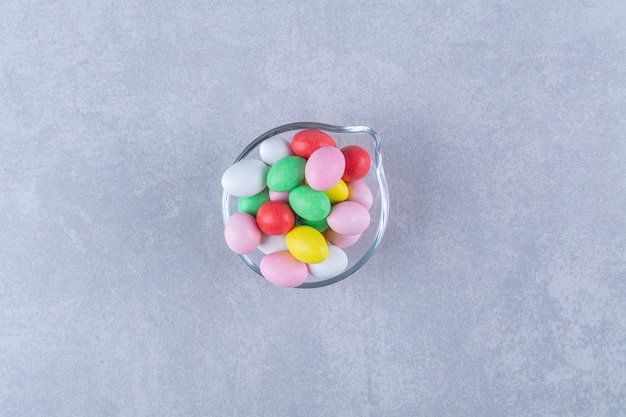 A glass cup full of colorful bean candies . 