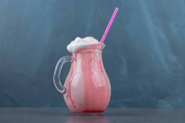 A glass cup full of sweet cold milkshake with chocolate syrup and pink straw. High quality photo