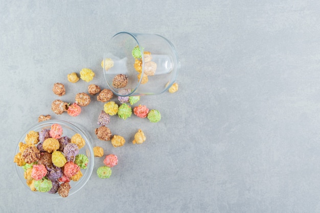 A glass cup full of sweet multicolored popcorn .  