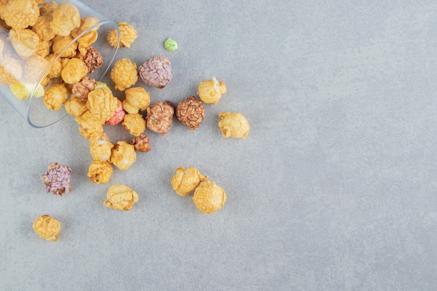 A glass cup full of sweet multicolored popcorn . 