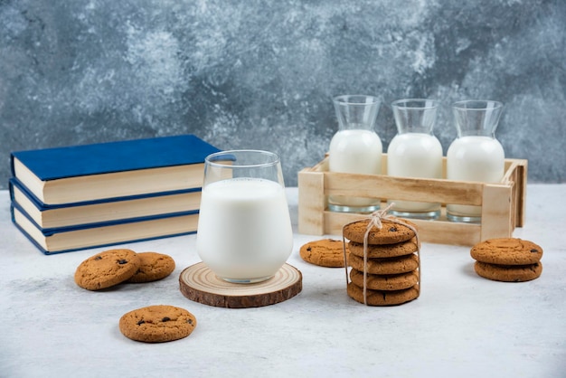 A glass cup of milk with chocolate cookies on a wooden board.