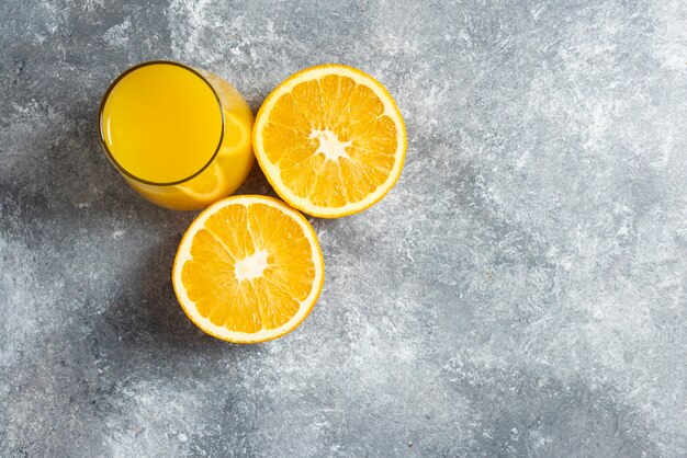 A glass cup of orange juice and slices of orange.