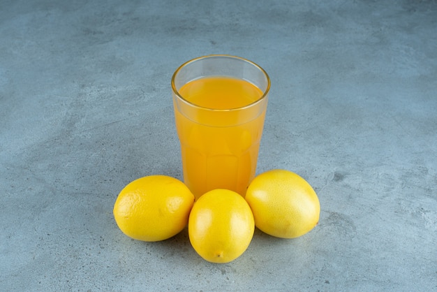 A glass cup of orange juice with fresh lemons . 