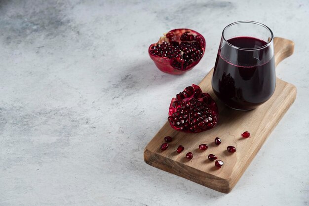 A glass cup of pomegranate juice on wooden board. 