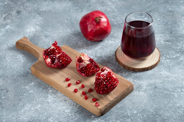 A glass cup of pomegranate juice on a wooden board.