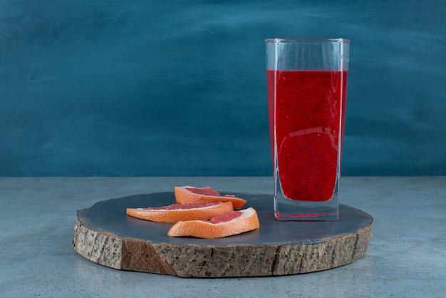 A glass cup of red juice with slices of grapefruit . 