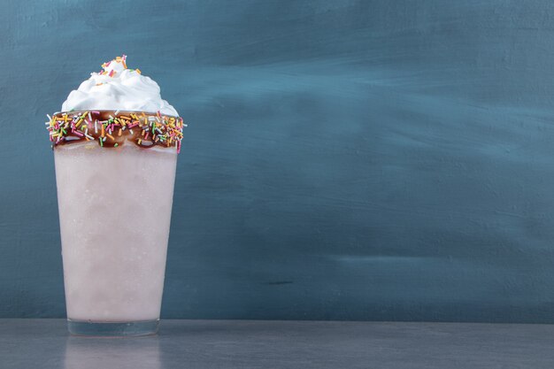 A glass cup of sweet milkshake with whipped cream