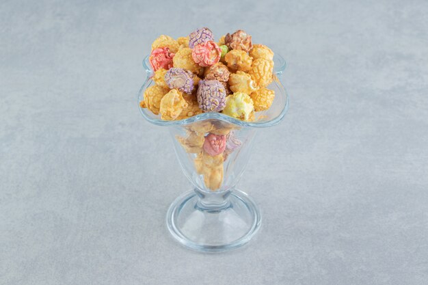 A glass cup of sweet multicolored popcorn .  