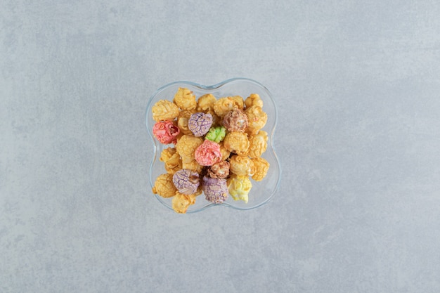 A glass cup of sweet multicolored popcorn .  