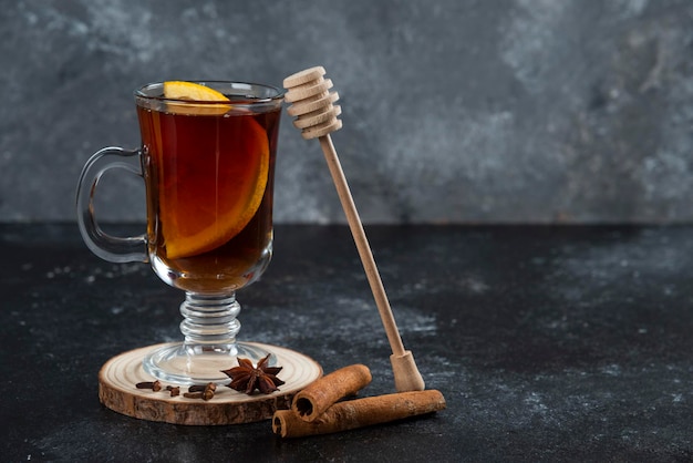 ガラスのお茶とシナモンスティックと木製のひしゃく。