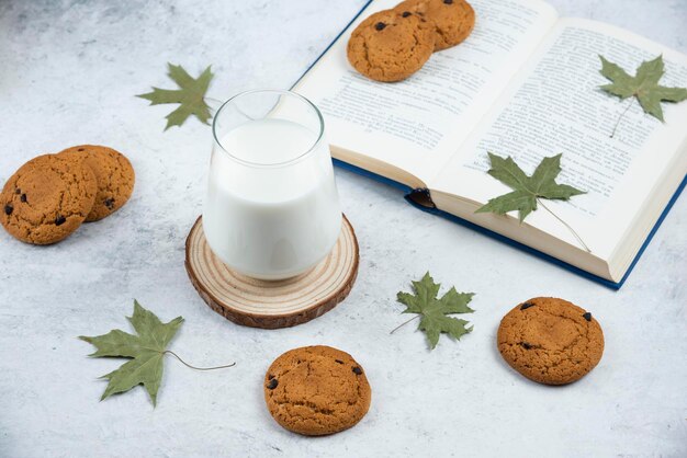 A glass cup with chocolate cookies on a wooden desk.