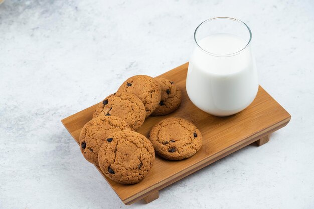 A glass cup with chocolate cookies on a wooden desk.