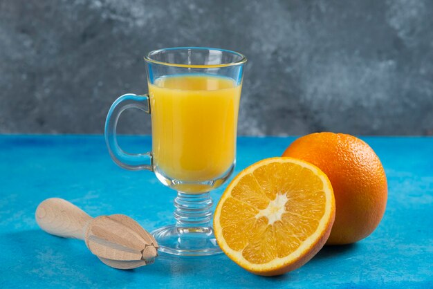 A glass cups of orange juice on blue.