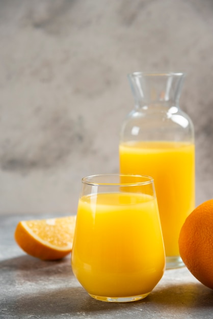 Стеклянные чашки апельсинового сока и дольки апельсина.