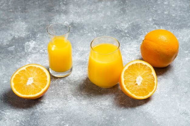 Glass cups of orange juice and a wooden reamer .