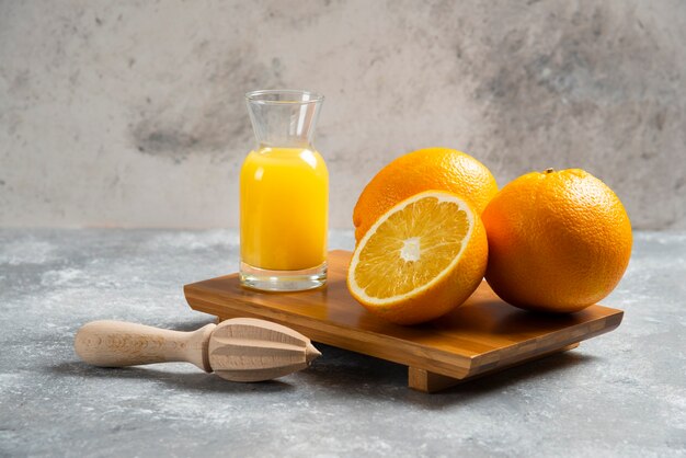 Glass cups of orange juice and a wooden reamer .