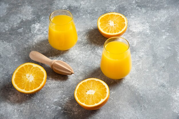 A glass cups of orange juice and a wooden reamer.