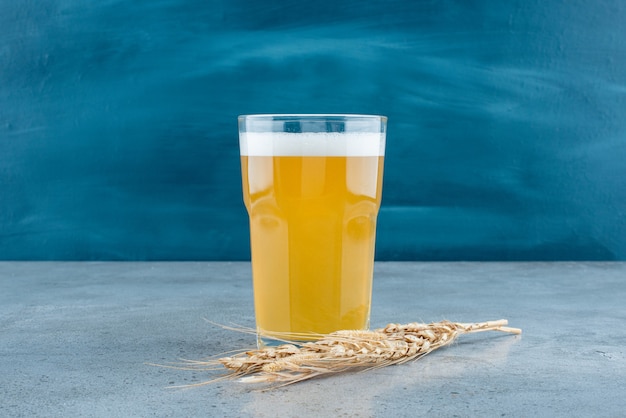 Стакан вкусного пива и пшеницы на сером фоне. Фото высокого качества
