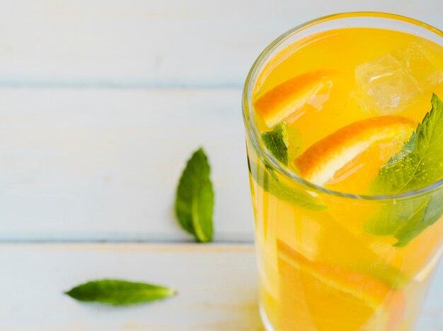 Glass of dewy orange juice with slices and mint