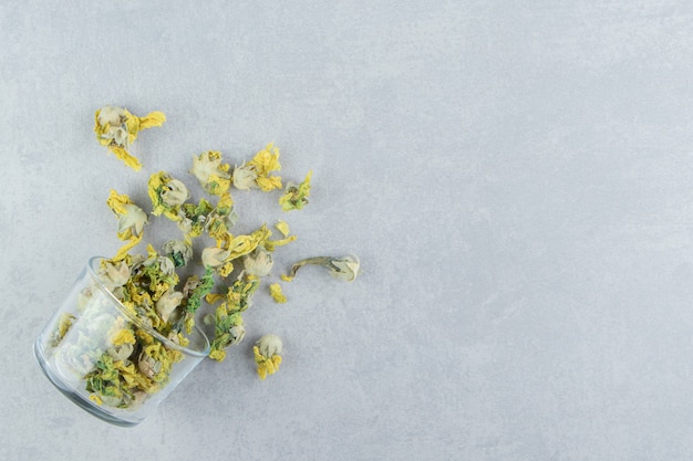 Glass of dry chrysanthemum flowers on stone table. 