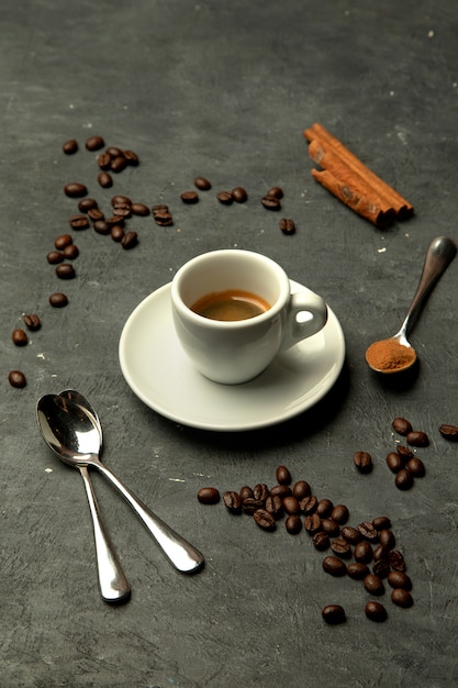 コーヒー豆で飾られた灰色の背景のエスプレッソコーヒーのグラス