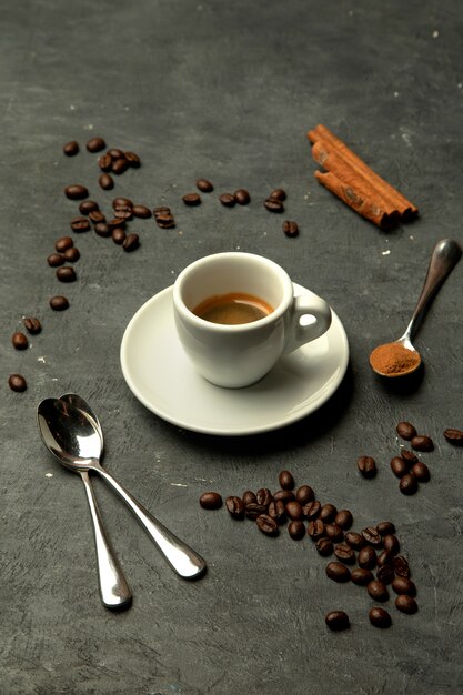 Glass of espresso coffee in grey background decorated with coffee beans