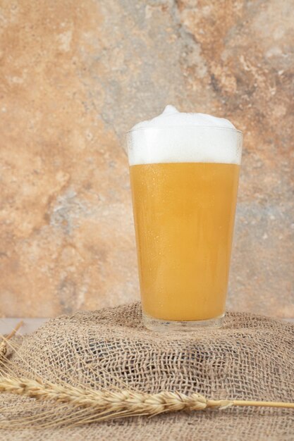 Glass of foamy beer on burlap wheat