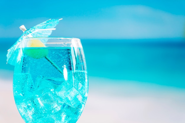 Glass of fresh blue drink decorated with olive and umbrella 