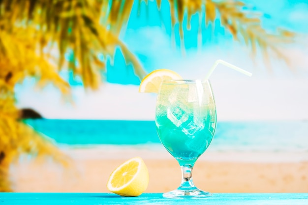 Glass of fresh blue drink with straw and sliced lime